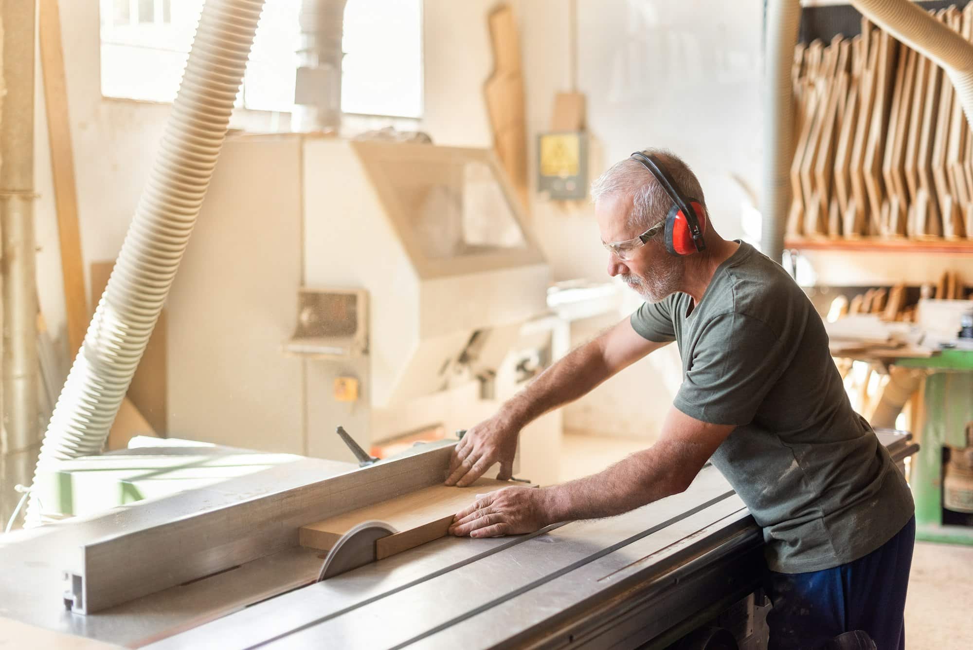 Man at work cutting timber on a sliding table saw